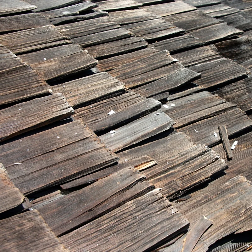 Rotting cedar shake roofing shingles are a sign of roof damage that needs to be addressed.